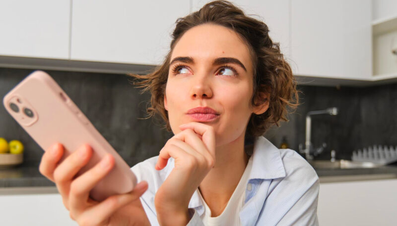 femme se posant des questions devant son smartphone